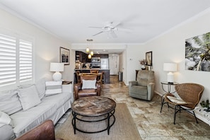 A living room with a sofa, armchairs, a coffee table, and a dining area with chairs and a table. - Win-san B203 (New Smyrna Beach)