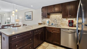 A modern kitchen with dark wooden cabinets, a stainless steel refrigerator, and a granite countertop.