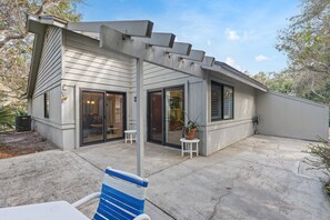 Ein Haus mit überdachter Terrasse, Schiebeglastüren und einem kleinen Garten.