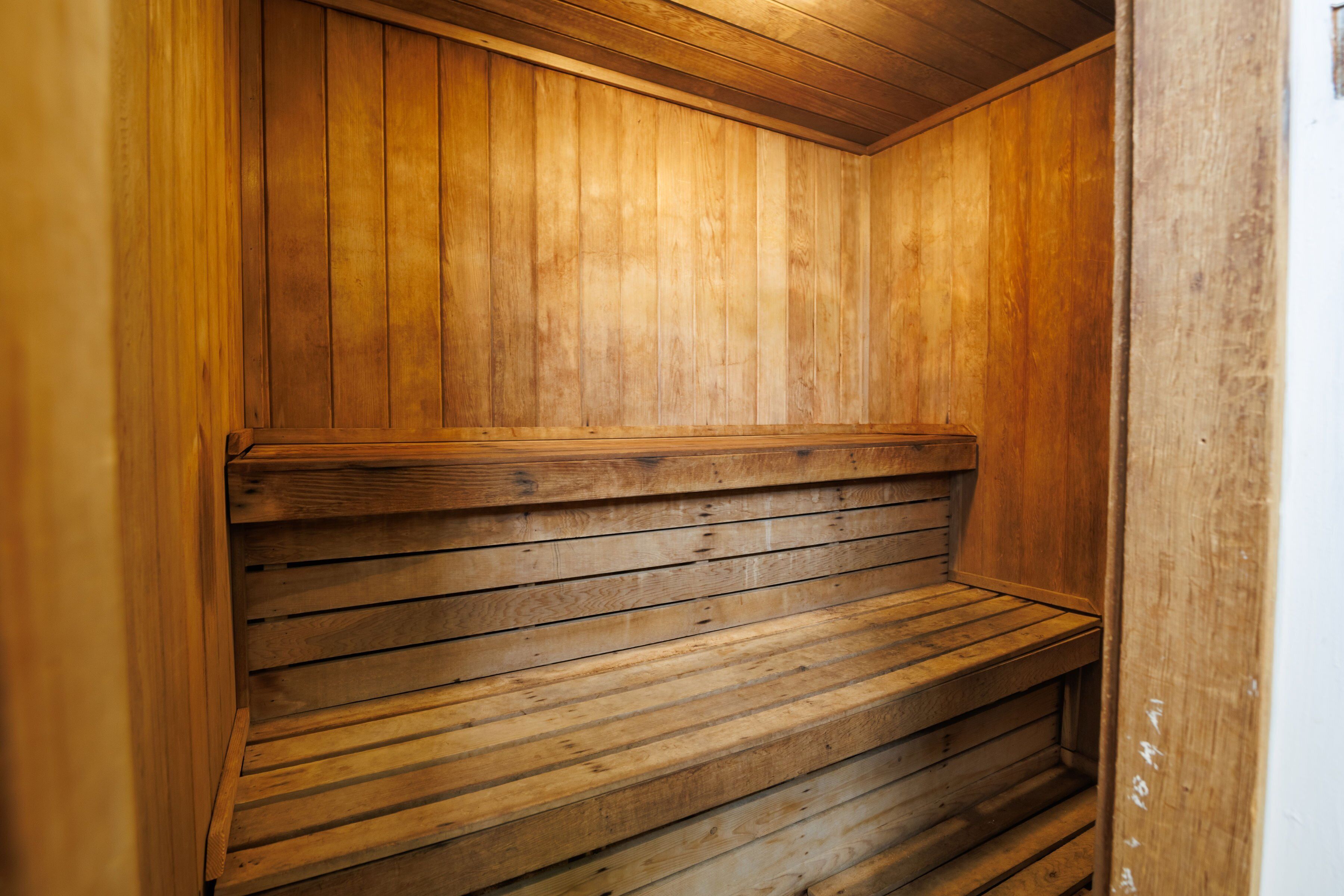 A wooden sauna with benches and a sloped ceiling.