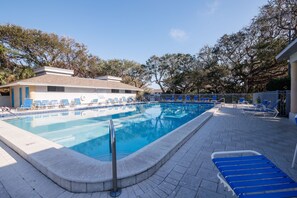 A swimming pool with lounge chairs and a building in the background. - Sea Woods Villa 4350 (New Smyrna Beach)