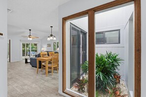 A modern interior with a dining area, a ceiling fan, and a view of a garden through a glass door. - Sea Woods Villa 4350 (New Smyrna Beach)