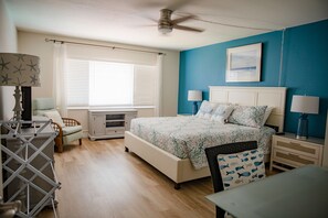A bedroom with a bed, nightstands, a desk, and a chair. - Win-san C213 (New Smyrna Beach)