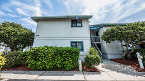 A two-story building with a flat roof, a small balcony on the second floor, and a visible address number. - Sea Woods Condo 169 (New Smyrna Beach)