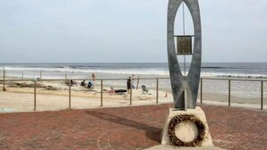A beachside walkway with a modern sculpture and a view of the ocean. - Win-san A101 (New Smyrna Beach)