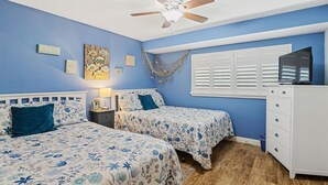 A bedroom with two beds, a ceiling fan, a TV, and a dresser. - Win-san A101 (New Smyrna Beach)