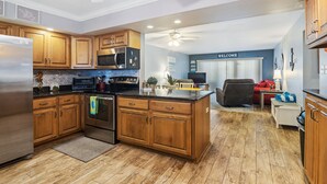 A spacious kitchen with wooden cabinets, a stainless steel refrigerator, and a built-in oven. - Win-san A101 (New Smyrna Beach)