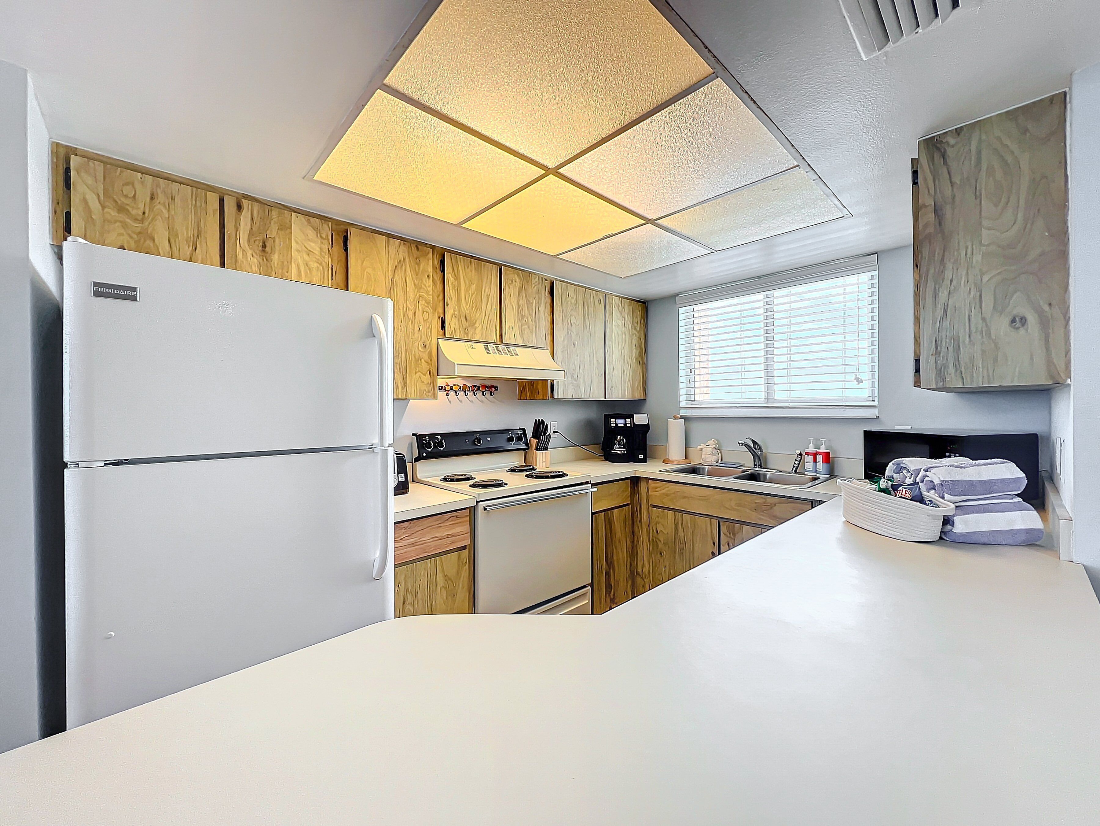 A modern kitchen with wooden cabinets, a white refrigerator, a stove, and a sink.