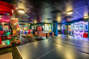 An indoor arcade with various gaming machines, a ping pong table, and colorful decorations. - Ocean Walk 2424b (Daytona Beach)
