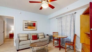 Ein Wohnzimmer mit einer Couch, einem Couchtisch, einem Esstisch mit Stühlen, einem Deckenventilator und einer Holzkabine.
