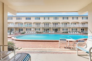 Ein Hotelinnenhof mit Swimmingpool, Liegestühlen und einer überdachten Sitzgelegenheit.
