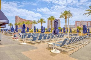 A poolside area with rows of sun loungers and umbrellas, palm trees, and hotel buildings in the background. - Vegas Luxury Trump Tower Studio 2615 (Las Vegas)