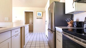 Una cucina con mobili bianchi, un frigorifero in acciaio inossidabile, un fornello e una macchina da caffè.