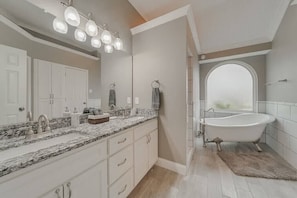 A modern bathroom with a freestanding bathtub, a large mirror, and a vanity with a granite countertop. - Poolside Summer 5BR 2bath Home With Gaming Room (Mesquite)