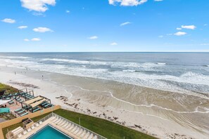 A beach view with a pool and lounge area. - Oceania Beach Club 803 (New Smyrna Beach)