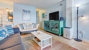 Ein Wohnzimmer mit Sofa, Couchtisch, Fernseher, Schrank und Stehlampe.