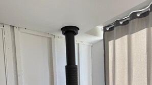 Ett rum med en svart vedeldad kamin, vita dörrar och ett fönster med gardiner.