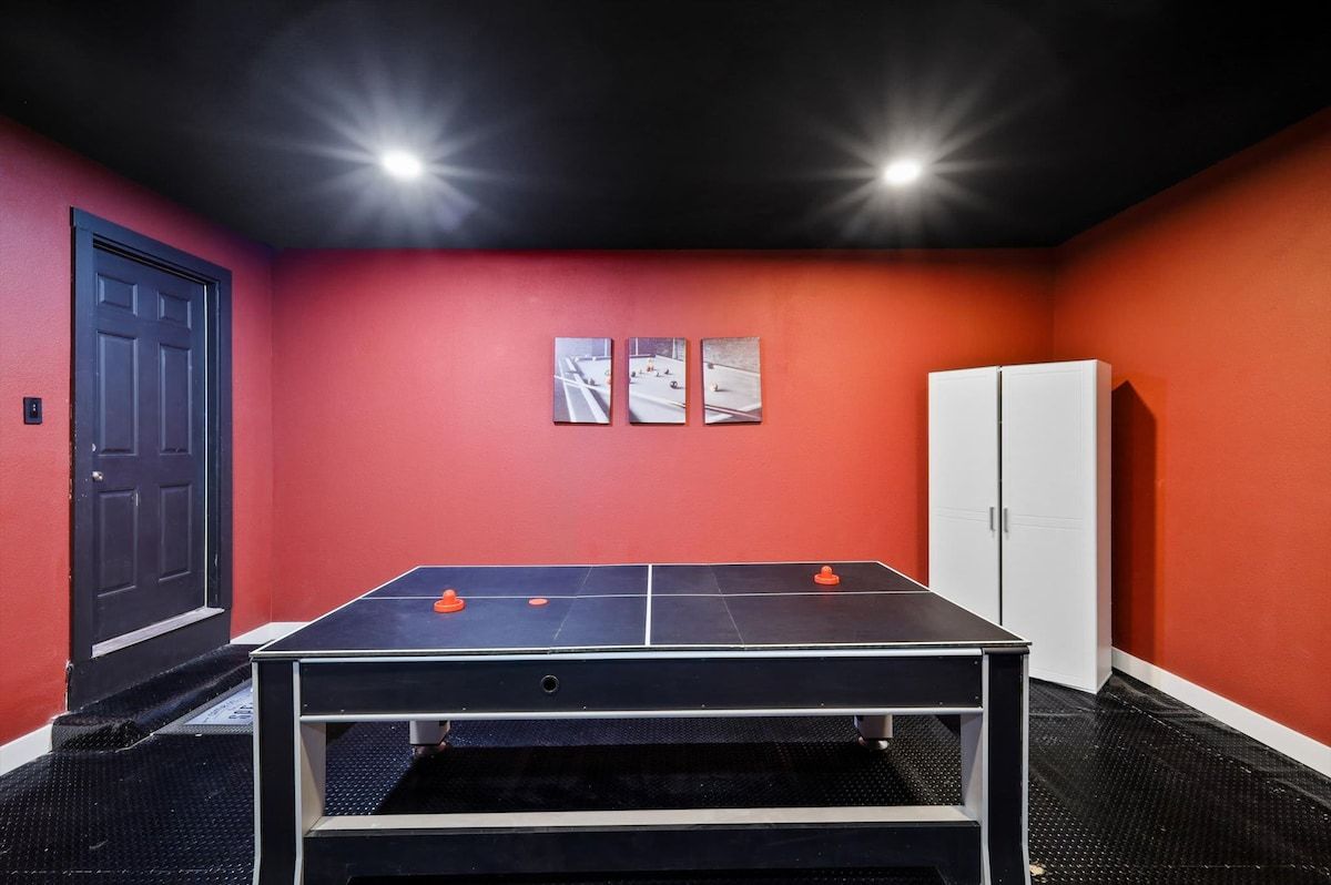 A ping pong table in a room with red walls, a white door, and a white cabinet.
