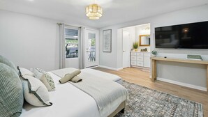 A bedroom with a bed, bedside tables, a TV, and a door leading to a balcony. - Spacious 5BR 3BA Retreat With Pool & Hot Tub (Duncanville)