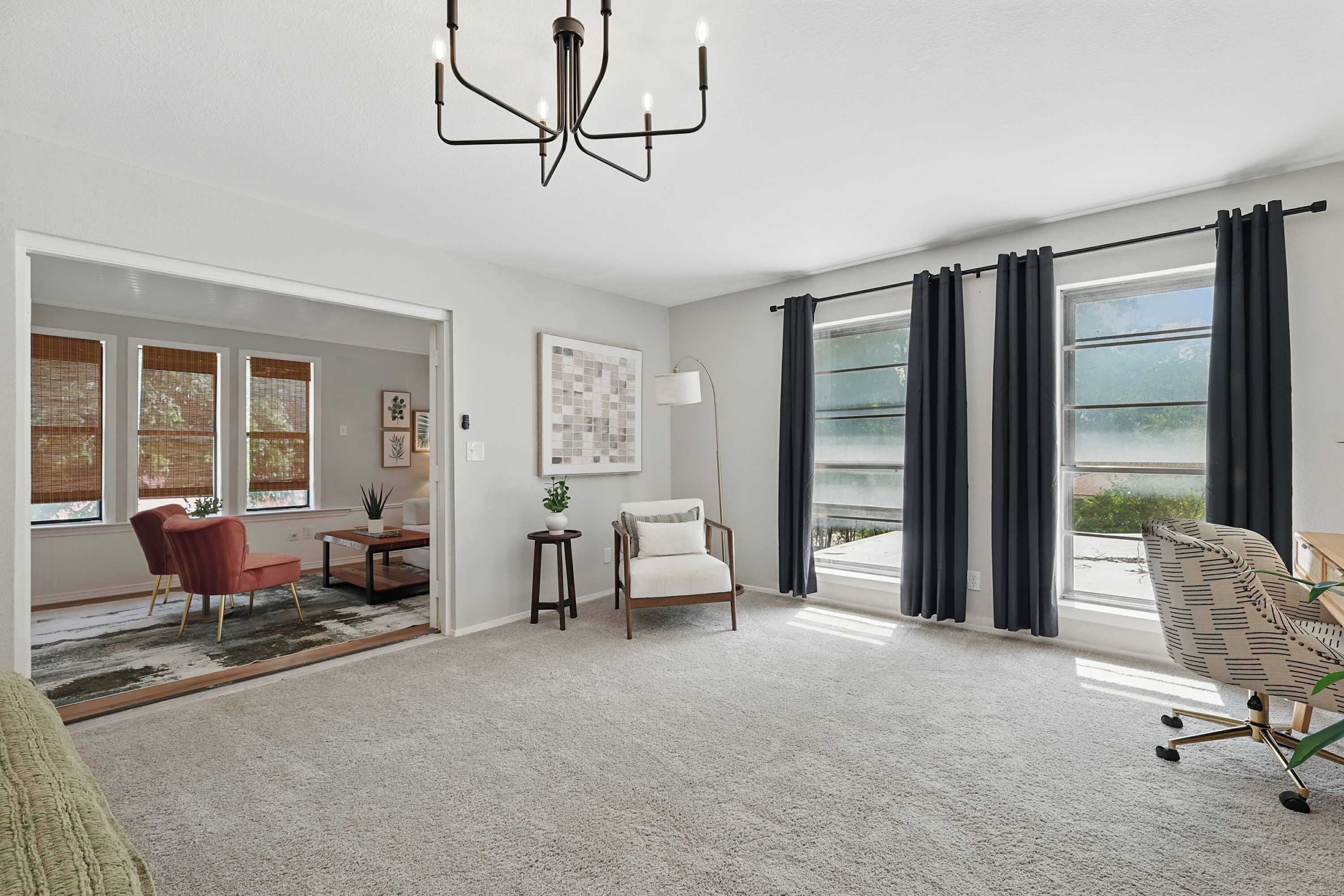 A spacious room with a large window, a chandelier, and a view of the outdoors.