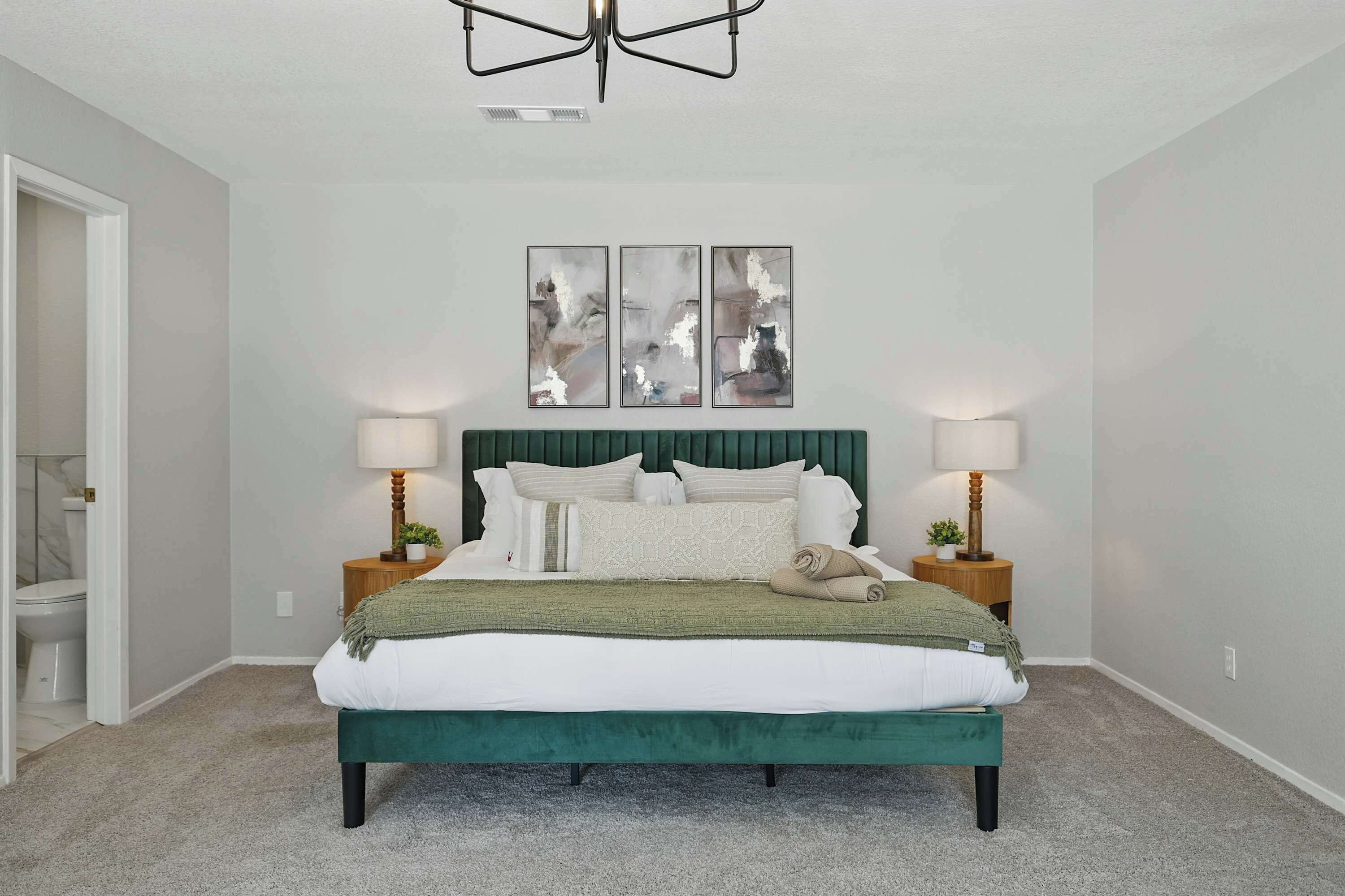 A bedroom with a bed, two bedside tables, a headboard, and wall art.