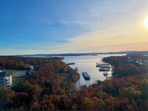 A waterfront property with a dock, boats, and a building surrounded by autumn foliage. - Spacious 2-bedroom condo in awesome Branson, MO over looking Table Rock Lake (Branson)
