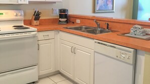 A kitchen with white cabinets, a stainless steel sink, a coffee maker, and a dishwasher. - Ocean Walk 2424a (Daytona Beach)