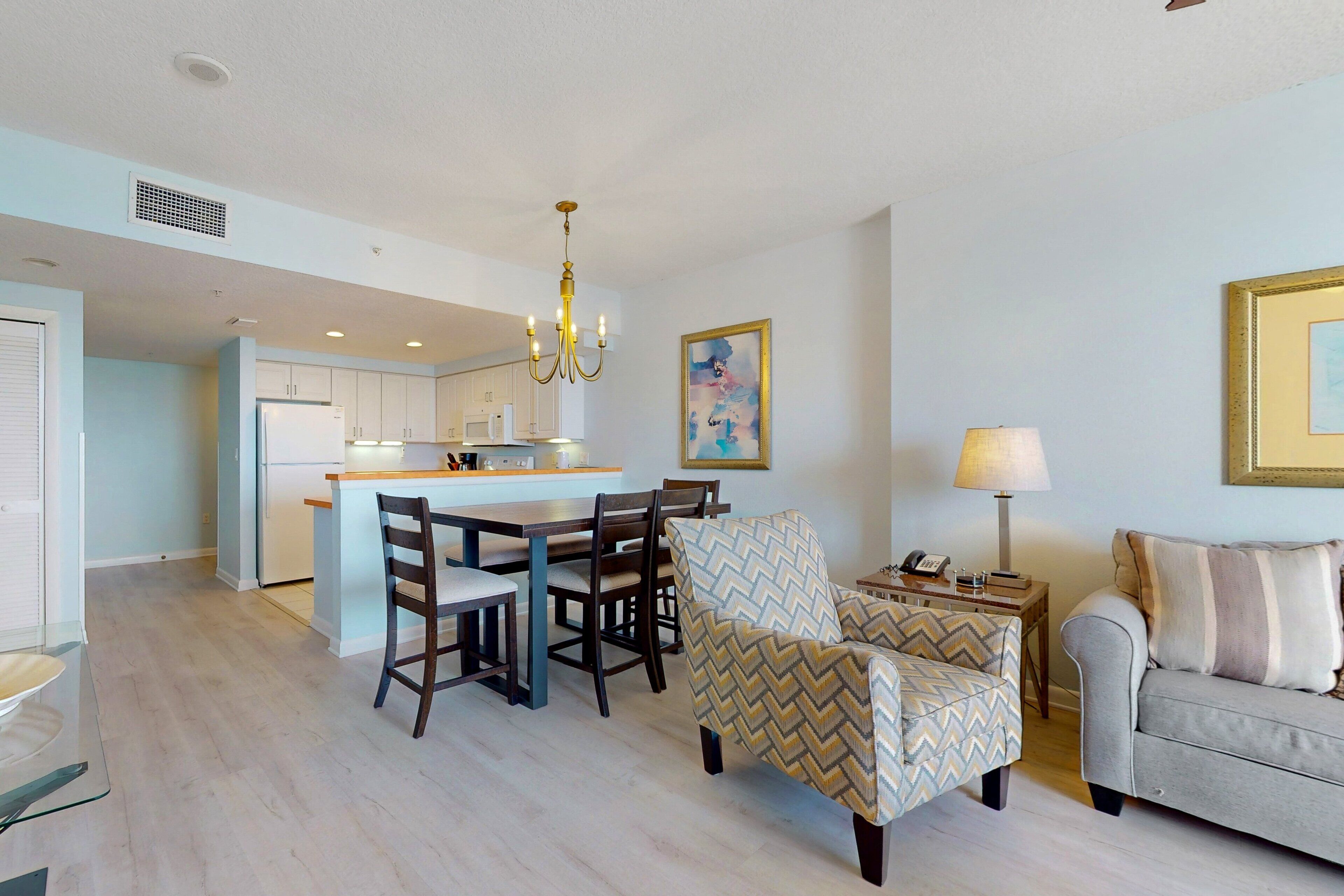 A modern kitchen with a dining area, a sofa, and a lamp.