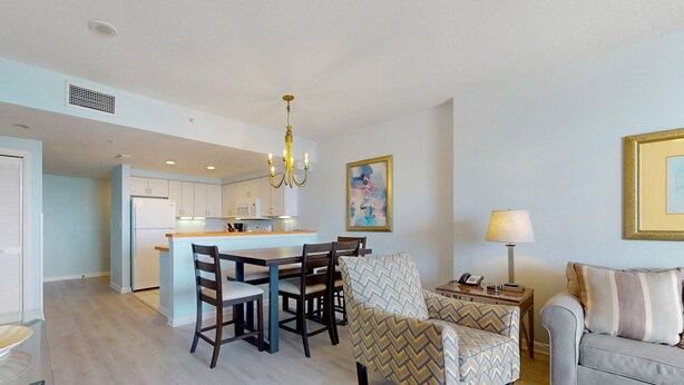 A modern kitchen with a dining area, a sofa, and a lamp. - Ocean Walk 2424a (Daytona Beach)
