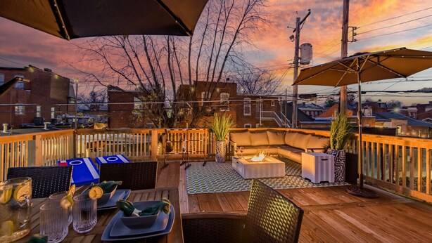 An outdoor patio with a checkered floor, wooden furniture, and a fire pit. - Modern Group Oasis: Hot Tub, Arcade & Fire Pit (St. Louis)