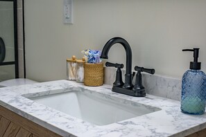 A bathroom sink with a black faucet, a soap dispenser, and a glass container with a blue lid. - asnfanfaknfckane (St. Louis)