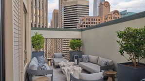 Una terrazza sul tetto con mobili da esterno moderni, piante in vaso e vista sullo skyline cittadino.