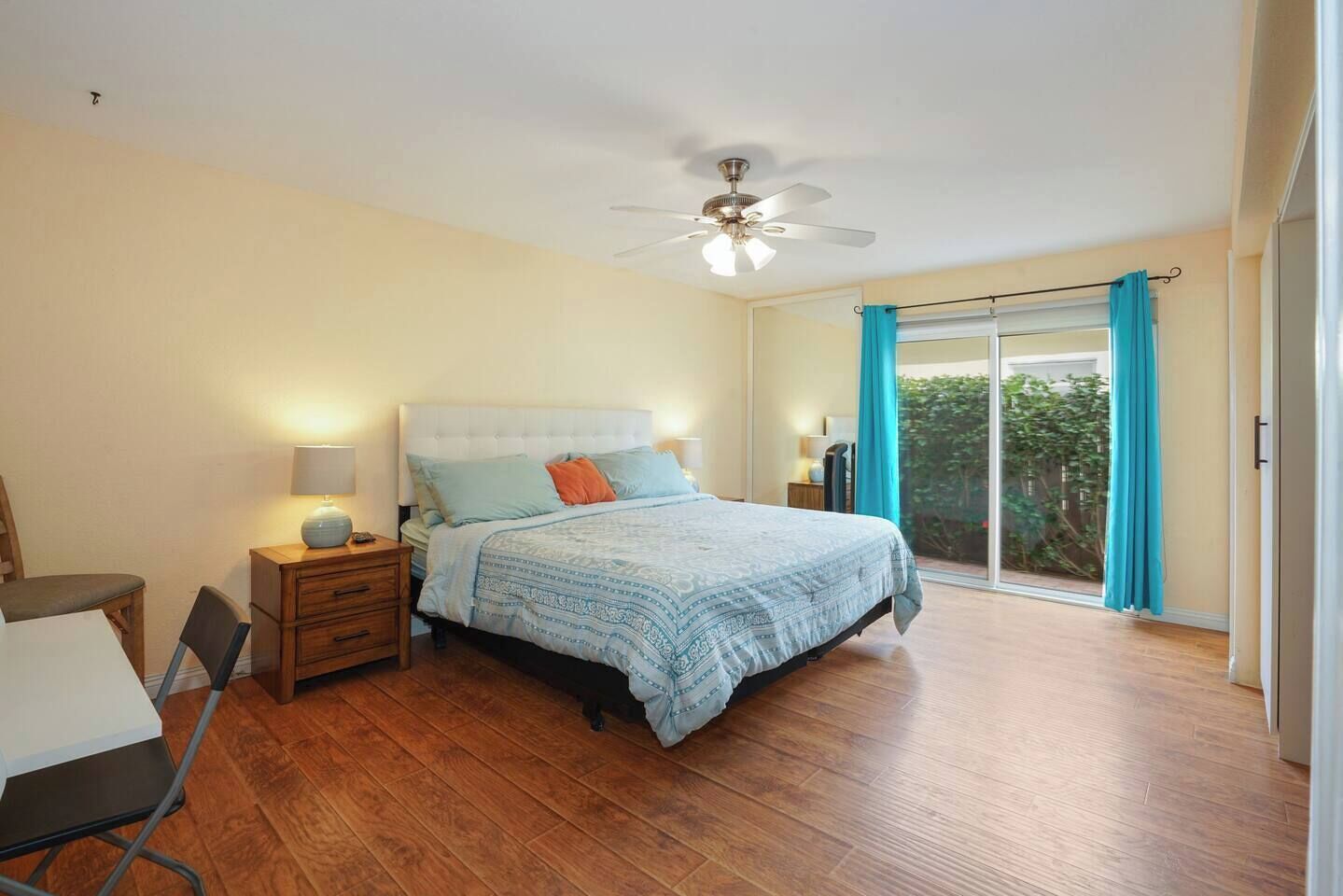 A bedroom with a bed, nightstands, a desk, and a window with curtains.