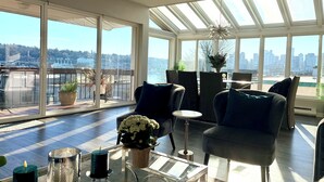 En moderne stue med et glas sofabord, behagelige møbler og udsigt over byen gennem store vinduer.