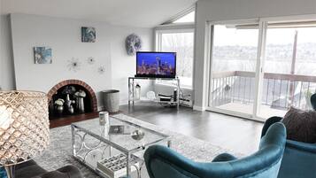 Un salon moderne doté d’un téléviseur à écran plat, d’une cheminée et d’un balcon offrant une vue sur la ville.