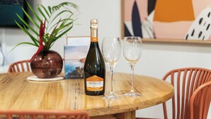 Une table en bois sur laquelle se trouvent une bouteille de Sané Prosecco Brut et deux verres à vin vides.