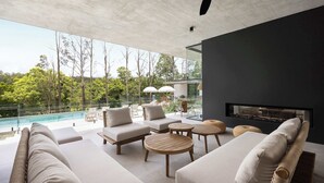 Uma área externa moderna com piscina, cadeiras de descanso e lareira.