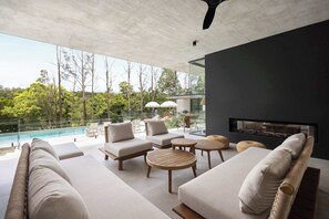 A modern outdoor living area with a pool, lounge chairs, and a fireplace. - Latitude 156 - Elevated Noosa Hinterland Luxury (Doonan)
