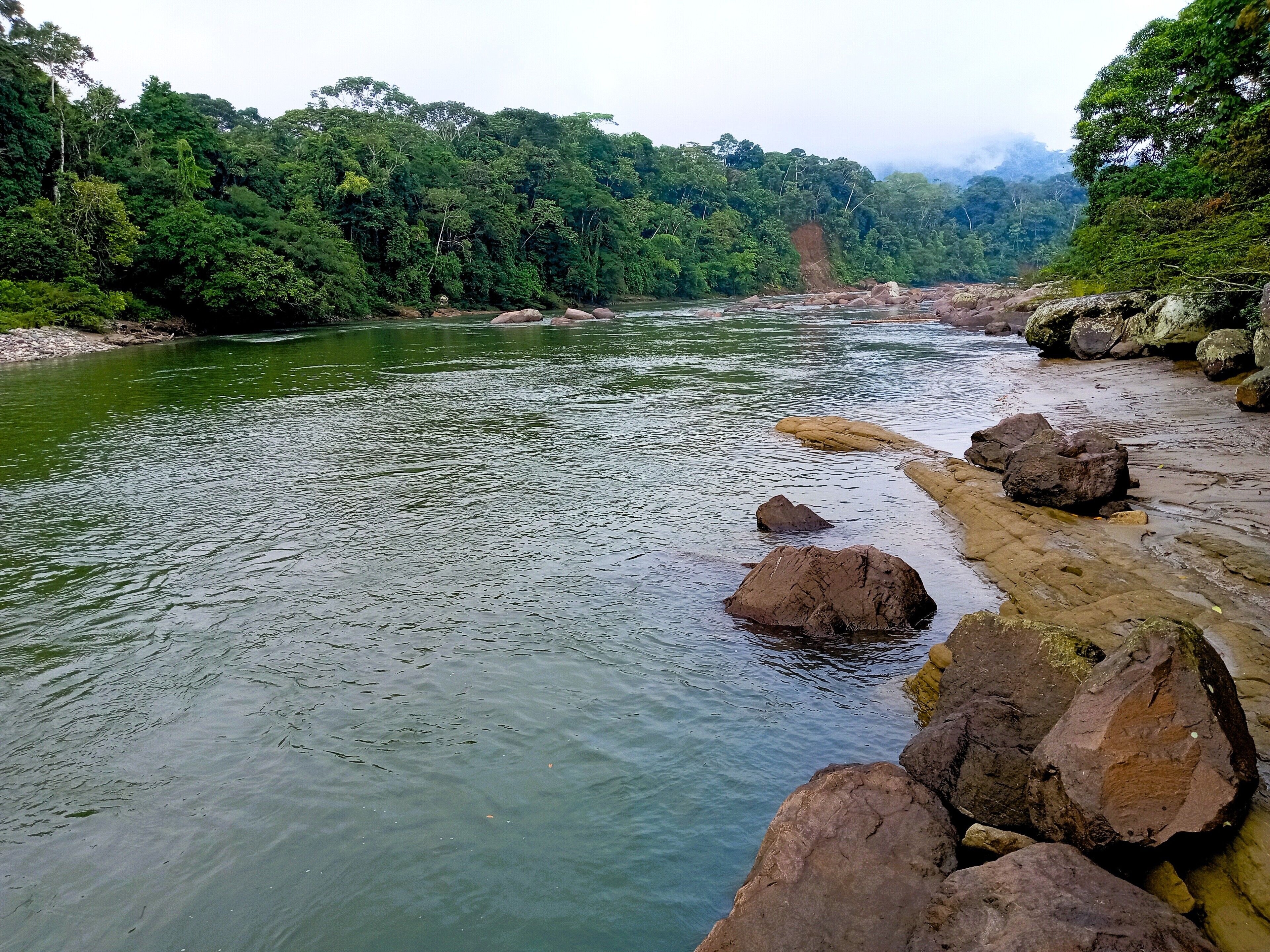 Une rivière bordée de rochers et d’une végétation luxuriante de chaque côté.