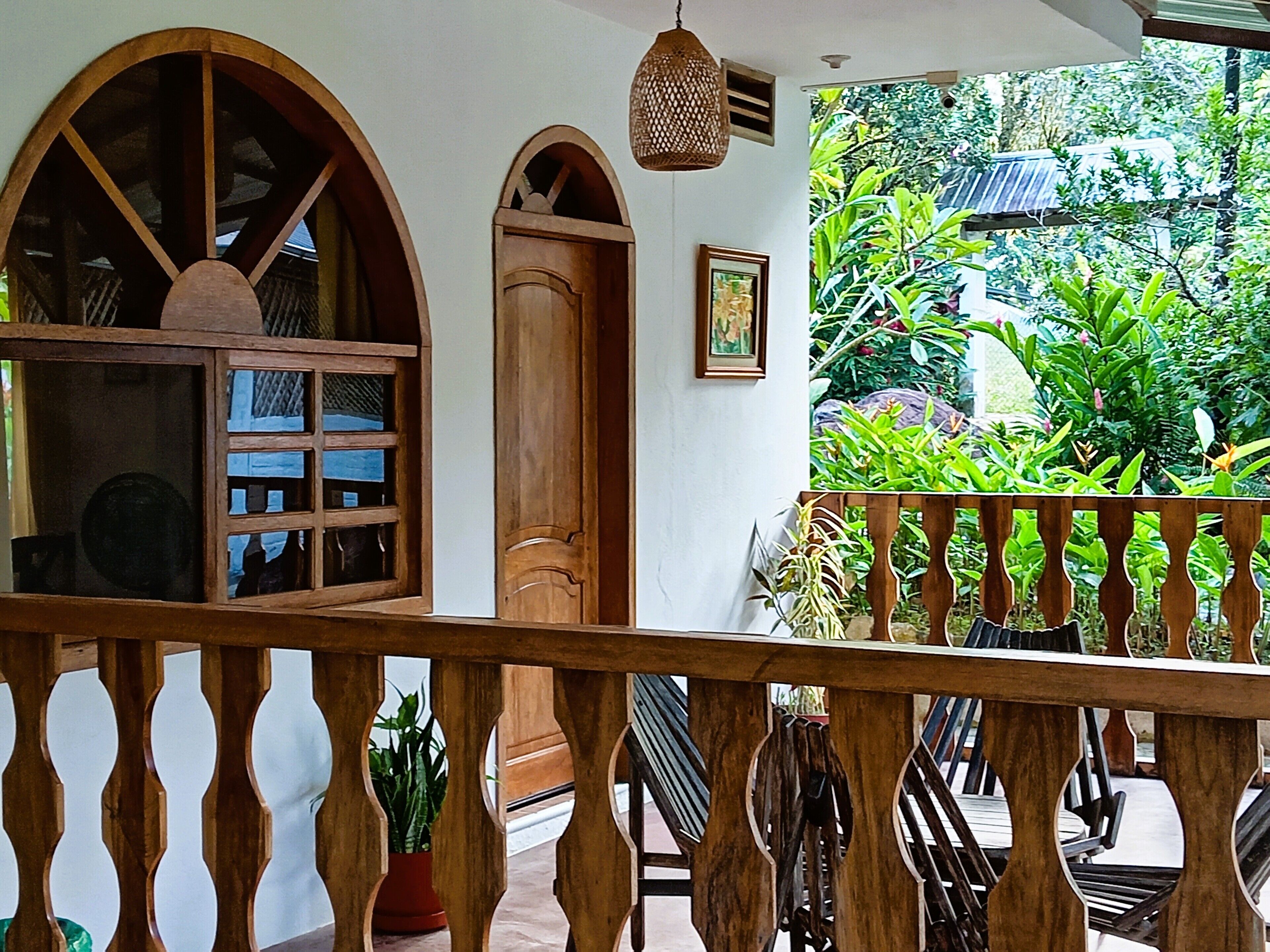 A wooden balcony with a railing, a door, and a window with a wooden frame.