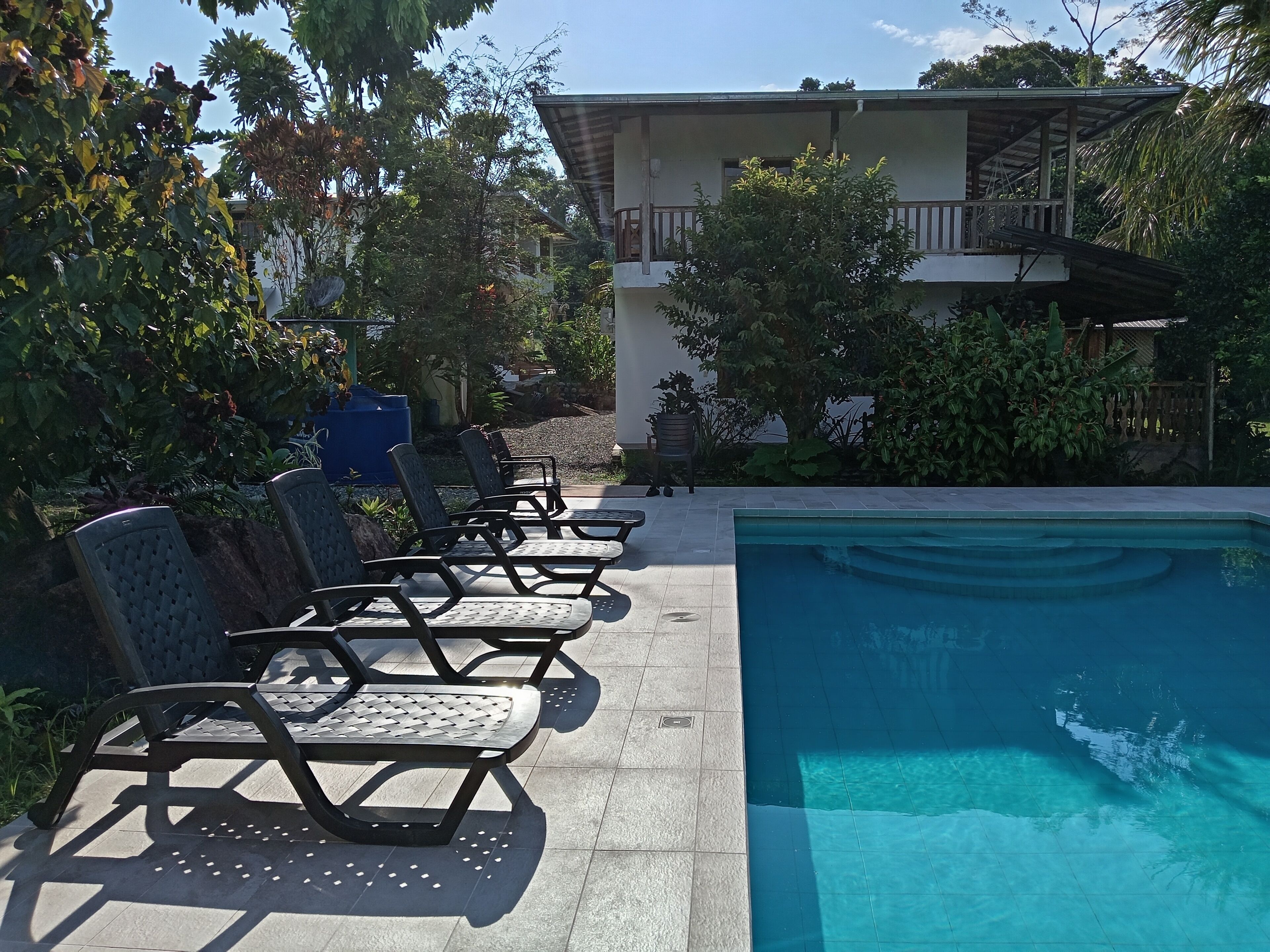 A pool area with lounge chairs and a building in the background.