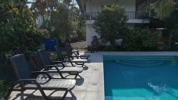 A pool area with lounge chairs and a building in the background.