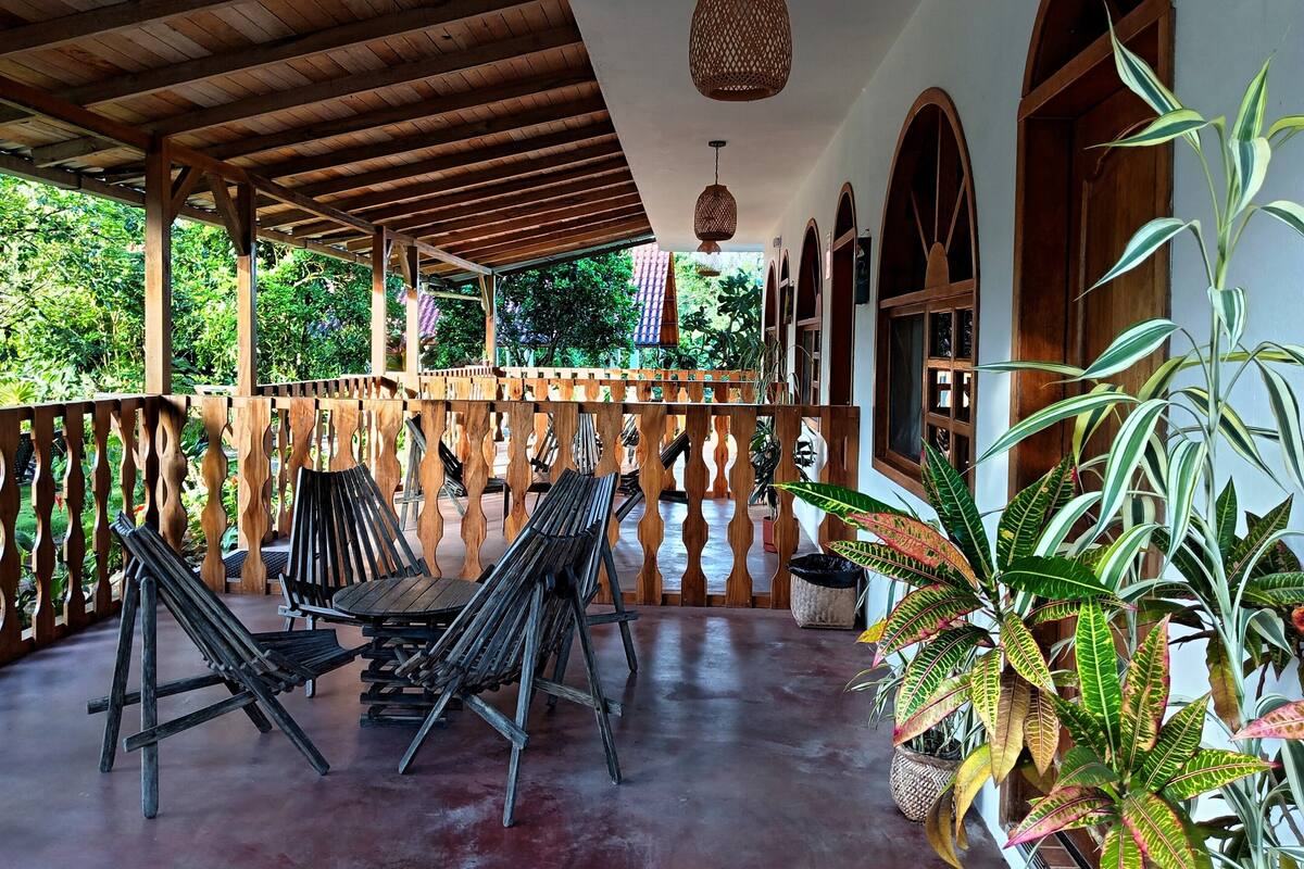 A covered outdoor seating area with wooden furniture and potted plants.