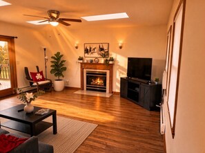 A living room with a fireplace, a television, and a ceiling fan. - Spacious 5BR • Valley & Lake Views • Near Cornell. Perfect for groups.  (Ithaca)