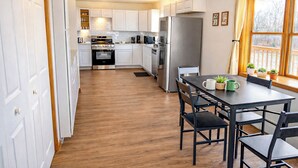 Une cuisine moderne avec des meubles blancs, des appareils en acier inoxydable et un coin repas comprenant une table et des chaises.