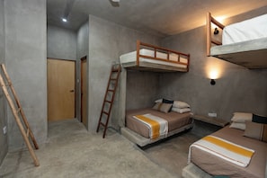Habitación con literas, una escalera, una puerta de madera y una lámpara en la pared.