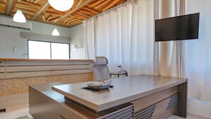A modern office with a large desk, a chair, a flat-screen TV, and a window with curtains. - Central Sosúa Studio: Pool, Fast Wi-Fi, Workspace (Sosúa)