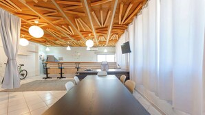 A conference room with a long table, chairs, a bicycle, and a kitchen area in the background. - Central Sosúa Studio: Pool, Fast Wi-Fi, Workspace (Sosúa)