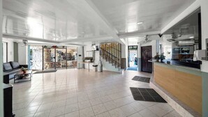 Un hall d’entrée spacieux comprenant un comptoir d’accueil, un escalier et un espace repas.