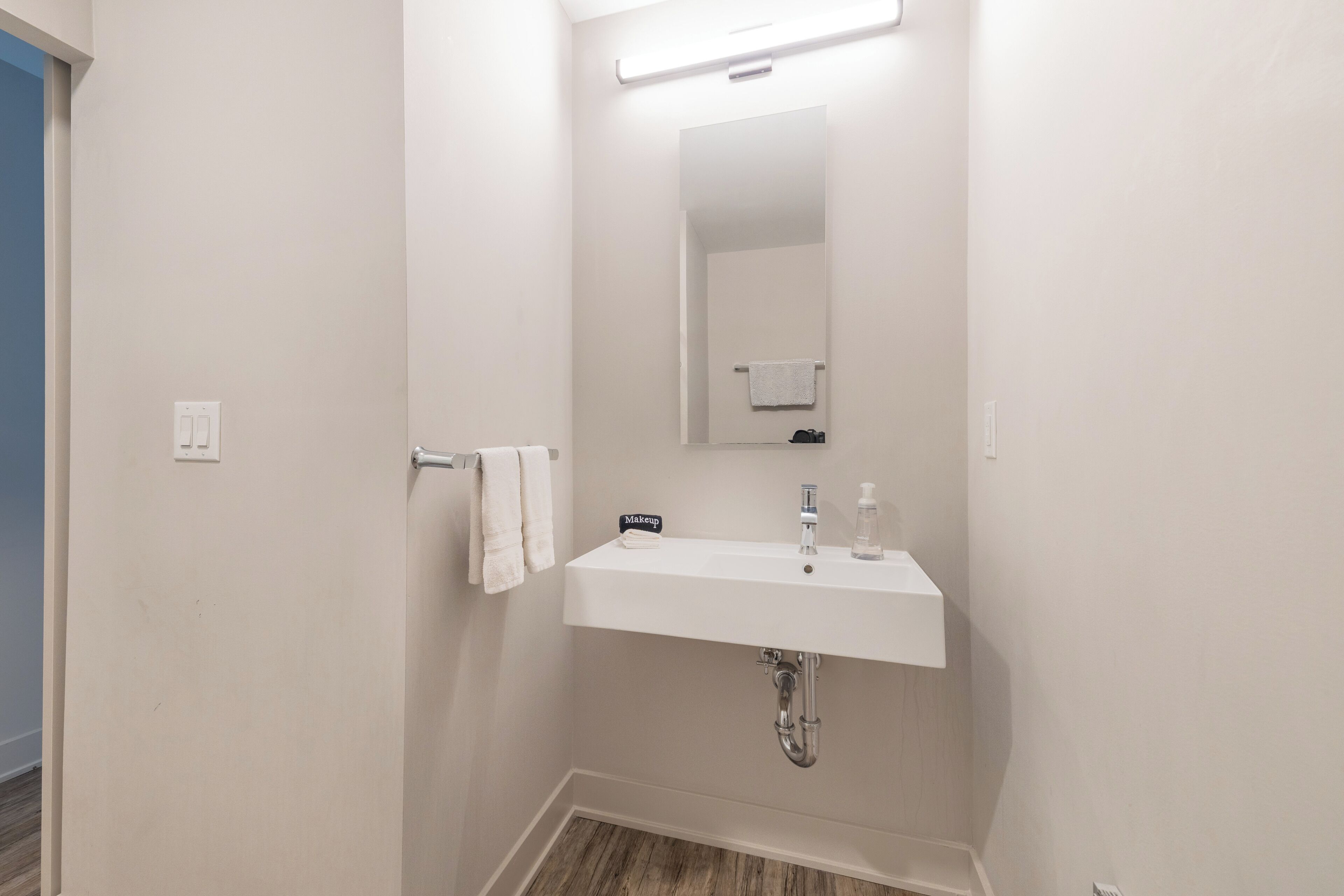 Une salle de bain avec un lavabo blanc, un miroir et un porte-serviettes.